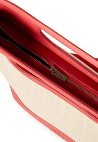 Borsa a mano rossa in pelle con corpo in tela beige intrecciata, dotata di chiusura con zip e doppi manici superiori per una facile portabilità.