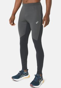 Fitted athletic leggings in dark gray with contrasting black panels, made of stretchy material, featuring a small logo on the upper leg.