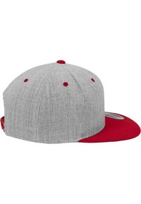 Cappello di tessuto grigio con visiera e dettagli rossi. Presenta una visiera piatta, una corona arrotondata e sei fori di ventilazione con eyelet rossi.