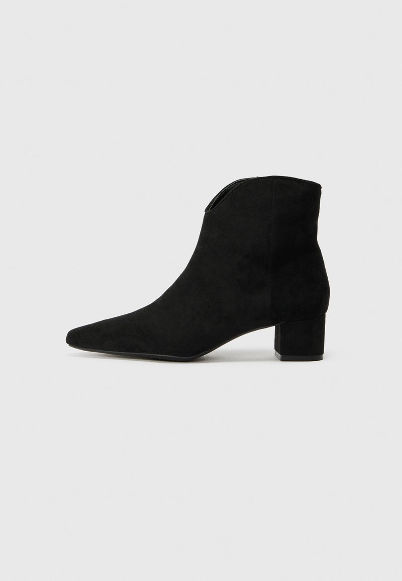 Bottines en daim noir à bout pointu et talon épais. Caractéristiques d'une texture lisse et d'un design épuré et minimaliste.