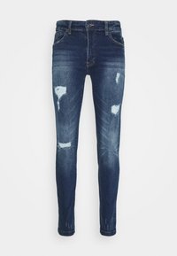 Slim-fit džíny v tmavě modré barvě s vybledlými částmi a odřenými dírami. Pět kapsový design, klasické zapínání na knoflík a poutka na opasek.