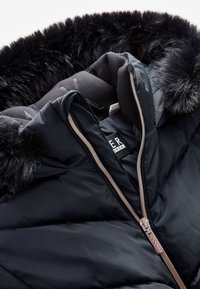 Sort pufferjakke med faux fur hætte, lynlåslukning, quiltet tekstur og et mærkat. Har en blank, glat overflade.