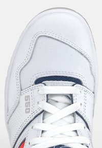 Baskets blanches en cuir perforé, lacets blancs, languette en mesh bleu marine, avec "550" embossé près des lacets.