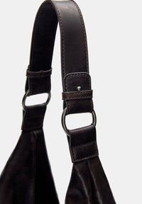 Cinghia della borsa in pelle marrone con una superficie liscia, caratterizzata da anelli metallici, fibbia regolabile e cuciture dettagliate lungo i bordi.