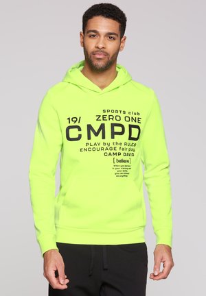 Felpa verde neon con tasca a marsupio frontale. Presenta grandi testi e loghi neri, polsini a coste e cappuccio con coulisse.