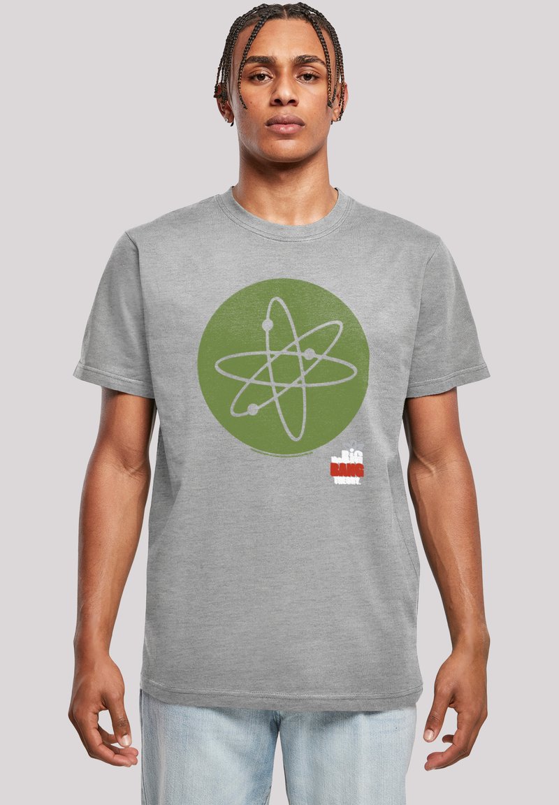 Camiseta de algodón gris con un gráfico circular verde que presenta un diseño de átomo. Incluye acentos en rojo y blanco en la parte inferior. Mangas cortas.