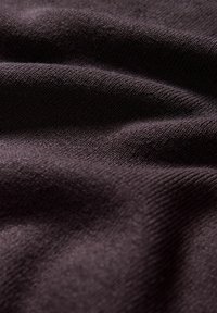 Ciemnobrązowa dzianina o delikatnej fakturze, z subtelnym prążkowaniem i gładkimi gradientami, układająca się w miękkie, falujące fałdy.