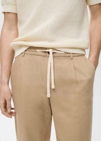 Beige linneblandade byxor med dragsko i midjan och sidofickor; något avslappnad passform med en slät textur och minimala sömnadsdetaljer.
