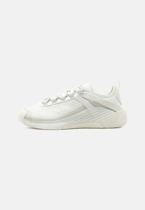 Weißer Sneaker mit niedrigem Profil, perforiertem Seitenpanel, gepolsterter Sohle, Schnürverschluss und Zuglasche an der Ferse, auf einfarbigem Hintergrund gezeigt.