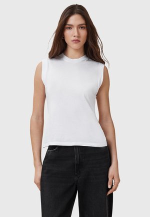 Top bianco senza maniche in cotone con colletto a girocollo, caratterizzato da una vestibilità morbida e una texture liscia. Abbinato a jeans in denim neri.