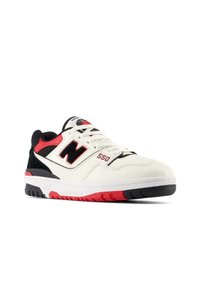 Baskets en cuir blanc avec des accents noirs, des détails rouges, des perforations sur les côtés et une semelle en caoutchouc. Présente un logo "N" bien en vue.