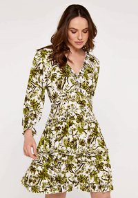 Blumenkleid mit weißem Hintergrund, das mit grünen und braunen Blattmustern verziert ist. Lange Ärmel, V-Ausschnitt, Rüschentaschen und leichtes Material.