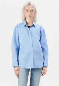 Camicia a righe blu e bianche, con bottoni, dal taglio rilassato, maniche lunghe e colletto, realizzata in tessuto leggero.