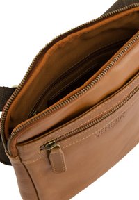 Brun læder crossbody taske med et lynlåset hovedrum, glat tekstur og en frontlomme. Indvendigt foret med orange stof.