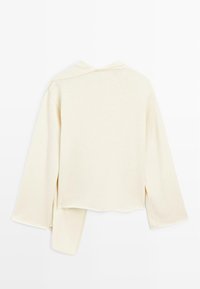 Pull crème à manches longues, ourlet asymétrique et coupe ample, présenté à plat sur fond blanc.