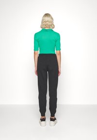 Top corto a righe verde abbinato a pantaloni jogger grigio scuro, con vita elastica e polsini aderenti. Sneakers con suola spessa.
