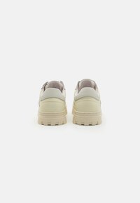 Sneakers in pelle crema con suola beige testurizzata, forma arrotondata, cuciture sottili e design a vita bassa. Presentano un pannello posteriore liscio e dettagli resistenti.