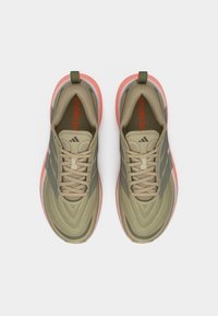 Ζευγάρι αθλητικά παπούτσια σε ελιά πράσινο και κοραλί χρώμα με κορδόνια, πλέγμα στο επάνω μέρος και μαλακές σόλες, φωτογραφημένα από πάνω.