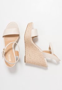 Sandali a wedge beige con tacco in juta textured, cinturini in pelle liscia e una cinghia alla caviglia regolabile per una vestibilità sicura.