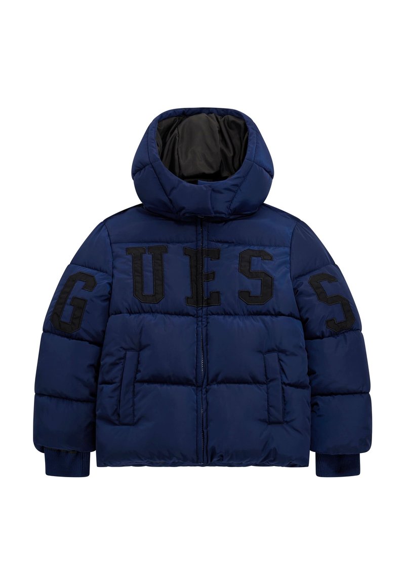 Giacca puffer blu navy con cappuccio alto, caratterizzata da grande scritta nera "GUESS" sul davanti e polsini a coste. Tessuto liscio con design trapuntato.