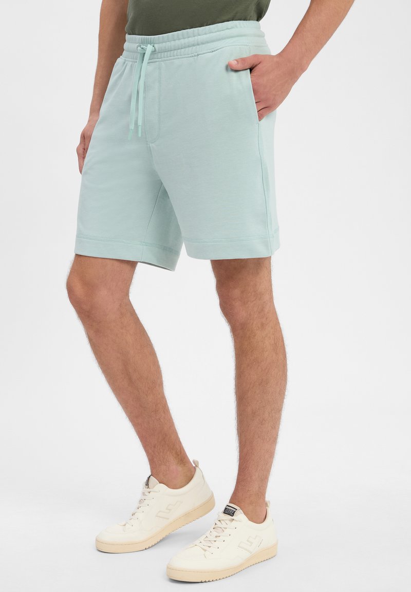 Helle blaue Baumwollshorts mit elastischem Bund, Kordelzug und seitlichen Taschen, die eine weiche Textur und einen entspannten Schnitt aufweisen.
