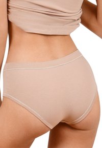 Mutande in cotone beige con design senza cuciture, vita alta e taglio dritto. Presentano una cucitura sottile attorno ai bordi.