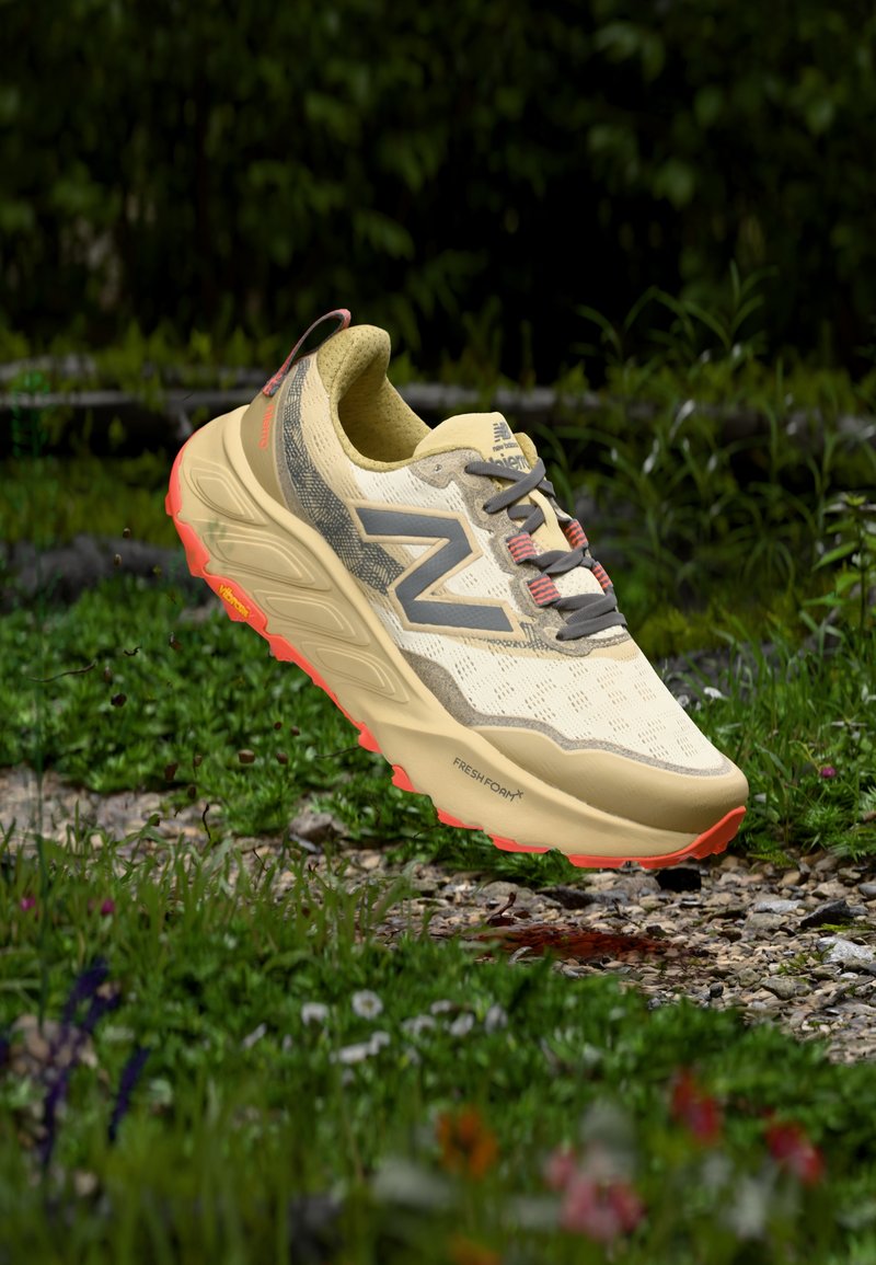 Chaussure de randonnée jaune clair avec une tige à motifs, des accents gris et une semelle extérieure orange vif. Comprend une semelle rembourrée et une surface texturée.