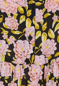 Tissu noir à motif floral rose et jaune ; présente des boutons sur le devant et un ourlet à volants en bas. Texture douce.