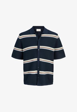 Dreng står iført en mørkeblå stribet kortærmet skjorte med knapper, grå shorts, cremefarvede sokker og beige sneakers på en hvid baggrund.