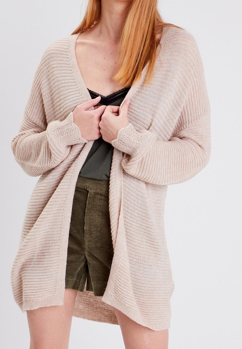 Ljusbeige öppen stickad cardigan med en mjuk textur, som har en avslappnad passform, långa ärmar och ribbade detaljer.