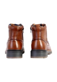 Bottines en cuir marron avec une texture lisse, fermetures éclair sur les côtés et une semelle en caoutchouc noir contrastante ; design classique à bout rond.