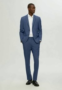 Ανοιχτό μπλε κοστούμι από ύφασμα με λεία υφή, διαθέτοντας κλείσιμο με ένα κουμπί, με κόψιμο στις πέτες και προσαρμοσμένο παντελόνι σε στενή γραμμή.