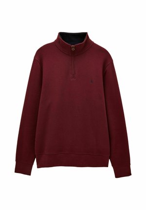 Bordo puolipitkä vetoketjullinen neule, jossa on pitkät hihat ja korkea kaulus. Vasemmassa rinnassa on pieni tumma logo.