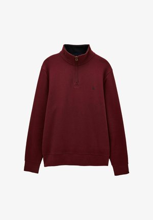 Bordo puolipitkä vetoketjullinen neule, jossa on pitkät hihat ja korkea kaulus. Vasemmassa rinnassa on pieni tumma logo.