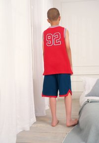 Red sleeveless basketball jersey with the number "92" in blue on the back, paired with dark blue shorts featuring red accents.