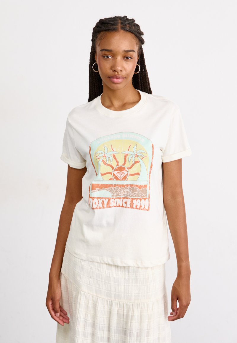 Crèmekleurig t-shirt met een grafisch ontwerp met palmbomen, zon en de tekst "ROXY SINCE 1990" in oranje en groene kleuren.
