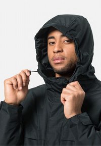 Zwarte hoodie met een gladde, matte afwerking. Voorzien van een verstelbare trekkoord en ritszakken aan de zijkanten. Strak, minimalistisch ontwerp.