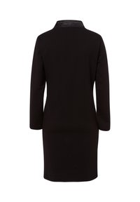 Robe noire à manches longues avec un col simple, texture lisse et coupe au genou. La vue de dos montre le design épuré et sans embellissement.