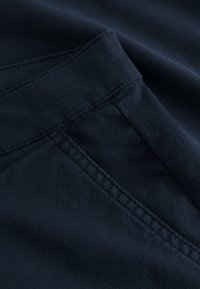 Artimos planas tamsiai mėlynos tekstūruotos audinio su dailiomis siūlėmis ir įsiūta kišene.