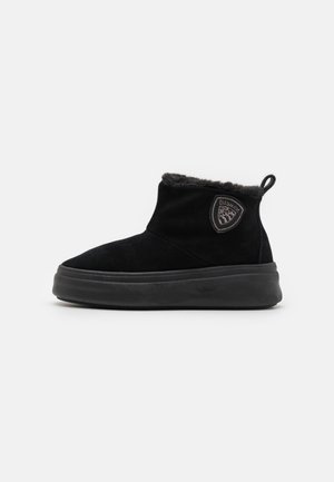 Stivaletti alla caviglia in suede nero con una fodera morbida, suola spessa e un logo laterale. Presentano un pratico tassello per facilitarne l'indosso.