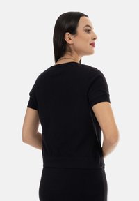 Maglietta nera a maniche corte in maglia con scollo rotondo e silhouette aderente, caratterizzata da una texture liscia e da delicati dettagli a coste sull'orlo.