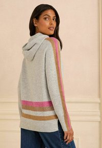 Sudadera con capucha gris con acentos en rosa, dorado y rayas rosas en las mangas y el dobladillo inferior. Textura suave, ajuste relajado y diseño de longitud media.
