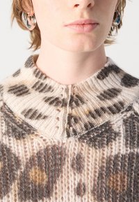 Pull en tricot avec un large col, base beige clair ornée de motifs marron et ocre, et un tissu en mélange de laine texturé et doux.