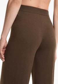 Pantaloni in maglia marroni con una texture morbida, design a gamba larga e una cintura ampia e liscia. Nessuna cucitura visibile o dettagli hardware.