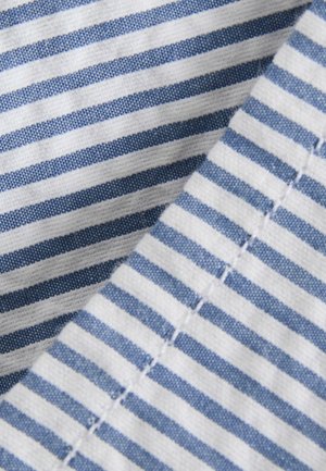 Ein Textil mit abwechselnden blauen und weißen Streifen, einer strukturierten Webart und sichtbaren Nähdetails entlang des Randes.