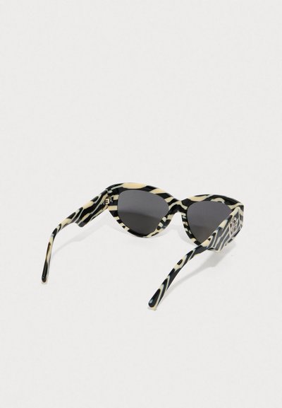 Sonnenbrille mit Zebra-Muster in Schwarz und Creme, Katzenaugenform, dunklen Gläsern und schlanken schwarzen Bügeln mit Logodetails.