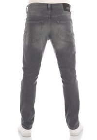 Vaqueros de mezclilla gris con un corte recto, cinco bolsillos, un ligero desgaste y una etiqueta de marca negra en la cinturilla.