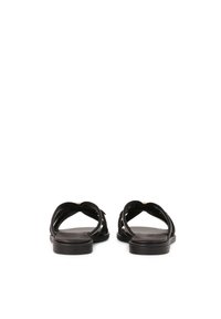 Schwarze Ledersandalen mit gekreuzten Riemen und flacher Sohle. Glatte Textur, offener Rücken und minimalistisches Design.