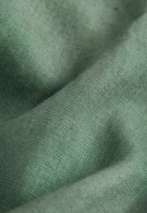 Groene linnen stof met een gestructureerd, geweven oppervlak. Het materiaal heeft een zachte, natuurlijke afwerking en subtiele kleurvariaties.