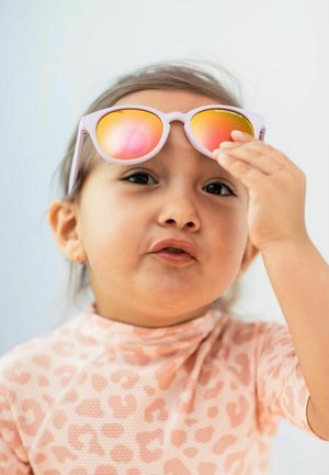 Vaaleanpunaiset aurinkolasit, joissa on heijastavat oranssit linssit, kevyet kehykset ja pyöreä muoto, joita lapsi pitää yllä kuosisessa vaaleanpunaisessa paidassa.